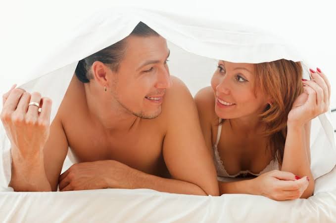 Happy couple smiling together in bed